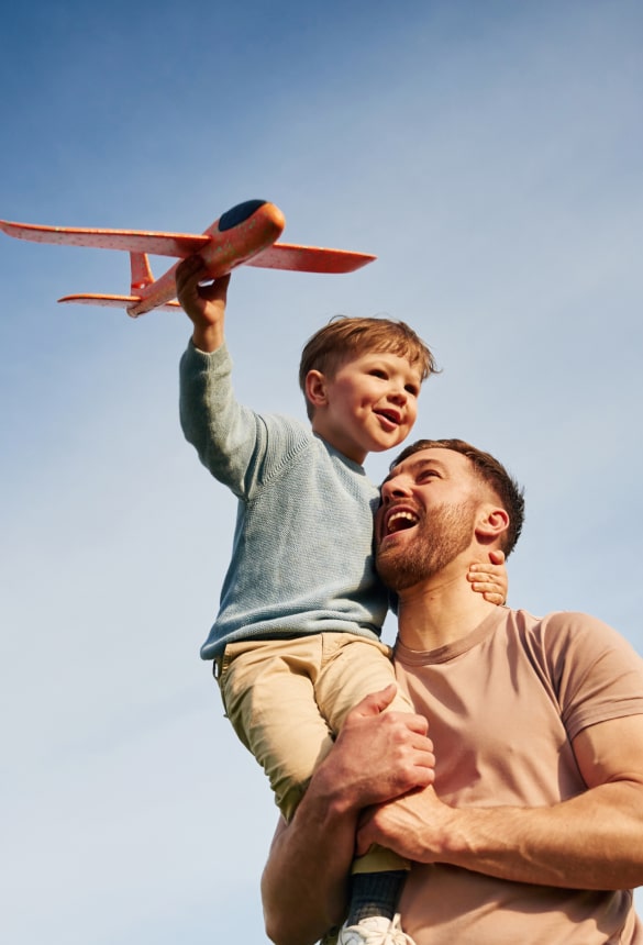 A father holding his son with a toy plane